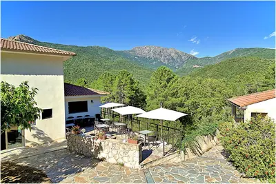 a patio with tables and umbrellas in front of a house at Auberge des Deux Sorru in Bains de Guagno
