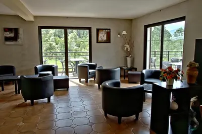 a waiting room with chairs and tables and windows at Auberge des Deux Sorru in Bains de Guagno