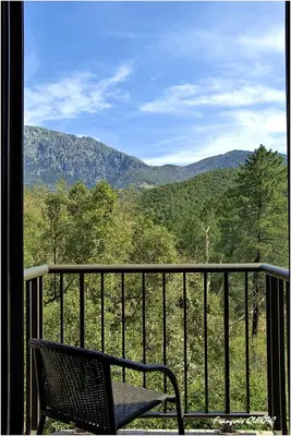 a chair on a balcony with a view of the mountains at Auberge des Deux Sorru in Bains de Guagno