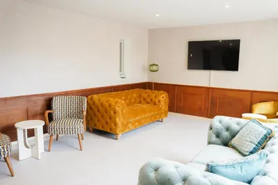 a living room with a couch and chairs and a tv at Hôtel 