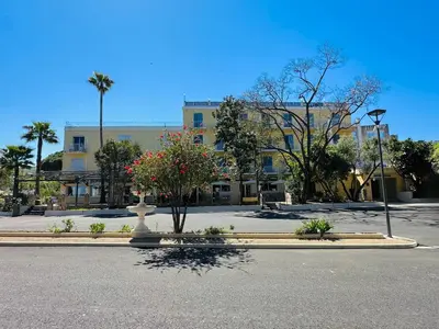 a street with a building and a statue in the middle at Hôtel 