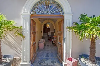 an archway leading into a hallway with palm trees at Mare E Monti - Hôtel de Charme in Feliceto