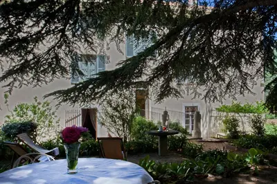 a vase of flowers sitting on a table under a tree at Mare E Monti - Hôtel de Charme in Feliceto