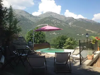 a patio with a table and chairs and an umbrella at Auberge Casa Mathea in Poggio-di-Venaco