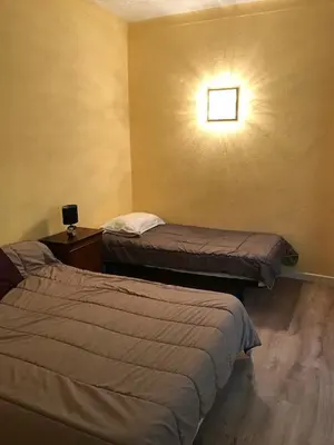 a room with two beds and a light on the wall at Auberge Casa Mathea in Poggio-di-Venaco
