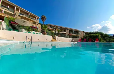 a swimming pool with blue water in front of a building at Residence Roc E Mare Cargèse in Cargèse