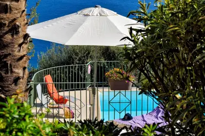 an umbrella and a chair next to a pool at Residence Roc E Mare Cargèse in Cargèse