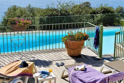 a swimming pool with a table and chairs next to a fence at Residence Roc E Mare Cargèse in Cargèse