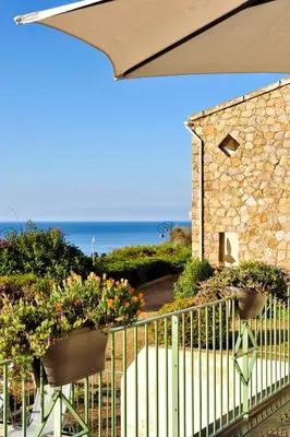 a balcony with flowers and a fence and the ocean at Residence Roc E Mare Cargèse in Cargèse