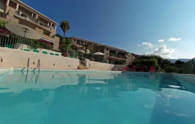 a large pool of blue water in front of a building at Residence Roc E Mare Cargèse in Cargèse
