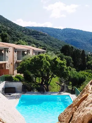 a large blue swimming pool in front of a house at Residence Roc E Mare Cargèse in Cargèse