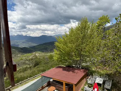 a view of a house with chairs and a tree at Ferme auberge du col de la vaccia in Olivese