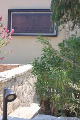 a sign on the side of a building with plants at La Villa in Favone