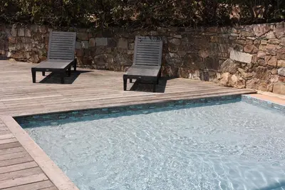 two chairs sitting on a wooden deck next to a swimming pool at La Villa in Favone
