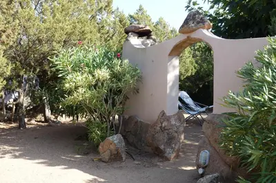 a garden with a statue of a rock and trees at Domaine de la Punta in Porto-Vecchio