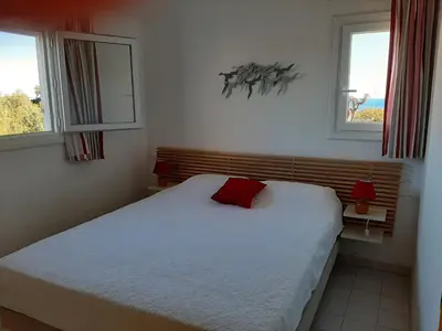 a bedroom with a bed with a red pillow on it at Domaine de la Punta in Porto-Vecchio