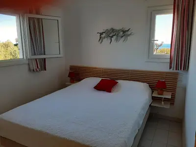 a bedroom with a bed with a red pillow on it at Domaine de la Punta in Porto-Vecchio