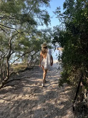 a woman in a hat walking down a trail at Domaine de la Punta in Porto-Vecchio