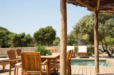 a wooden table and chairs next to a swimming pool at U Capu Biancu in Bonifacio