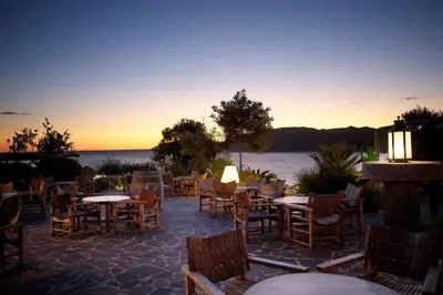 a patio with tables and chairs with a view of the water at U Capu Biancu in Bonifacio