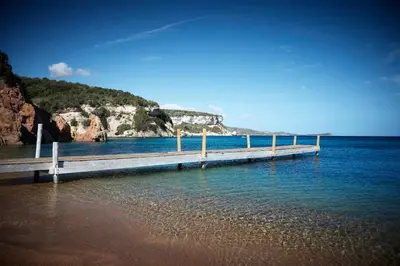 a dock in the water with a mountain in the background at U Capu Biancu in Bonifacio