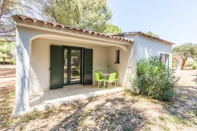 a small house with a patio with green chairs at Kilina in Porto-Vecchio