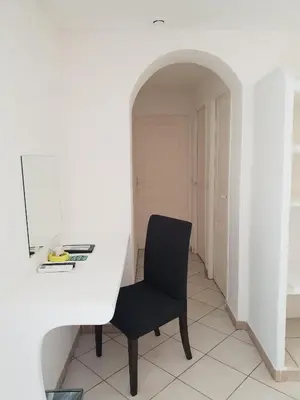 a black chair in a white room with a mirror at Kilina in Porto-Vecchio