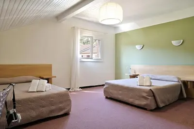 a bedroom with two beds and a window at Hôtel de Porticcio in Porticcio