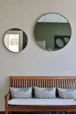 two mirrors above a wooden bench with two mirrors at Hôtel de Porticcio in Porticcio