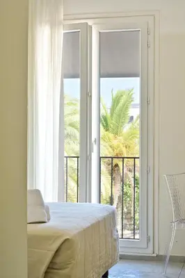 a bedroom with a bed and a large window at Hôtel de Porticcio in Porticcio