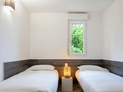 two beds in a room with a window at Apartment MB4 piscine by Interhome in Moriani Plage