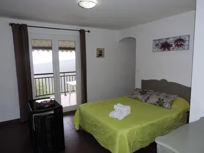 a bedroom with a green bed and a balcony at Apartment Fougère by Interhome in Partinello