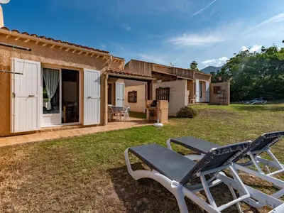 a patio with two chairs in front of a house at Holiday Home La Pinède- bungalow 4 pers- by Interhome in Sagone