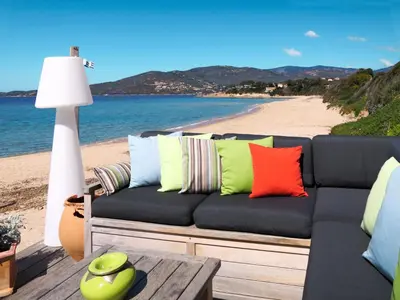 a couch with colorful pillows sitting on a beach at Holiday Home La Pinède- bungalow 4 pers- by Interhome in Sagone