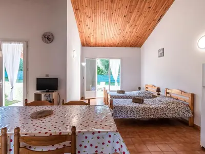 a room with two beds and a table and a television at Holiday Home La Pinède- bungalow 4 pers- by Interhome in Sagone