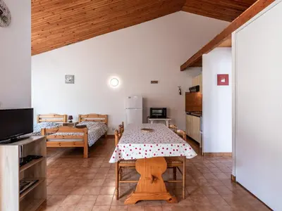 a living room with a table and a bedroom at Holiday Home La Pinède- bungalow 4 pers- by Interhome in Sagone