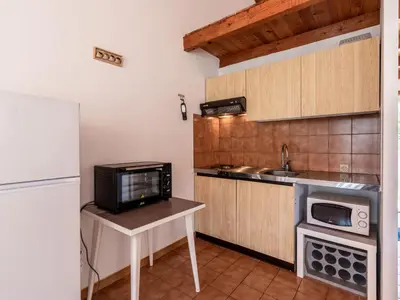 a small kitchen with a microwave and a refrigerator at Holiday Home La Pinède- bungalow 4 pers- by Interhome in Sagone