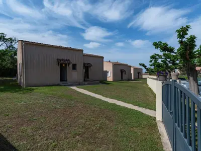 a building with a fence next to a yard at Holiday Home La Pinède- bungalow 6 pers- by Interhome in Sagone