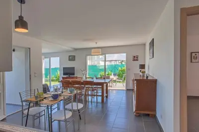 a living room with tables and chairs and a dining room at Villa Jardins de la Mer in Poggio-Mezzana