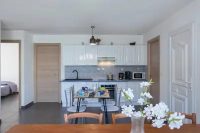 a kitchen with white cabinets and a table with chairs at Villa Jardins de la Mer in Poggio-Mezzana