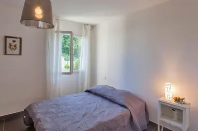 a bedroom with a bed and a window at Villa Jardins de la Mer in Poggio-Mezzana