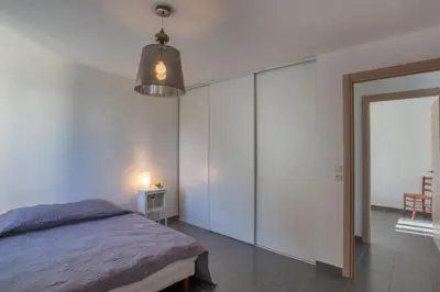 a bedroom with white walls and a bed and a lamp at Villa Jardins de la Mer in Poggio-Mezzana