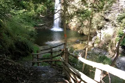 a waterfall in the middle of a river with a fence at Villa Jardins de la Mer in Poggio-Mezzana