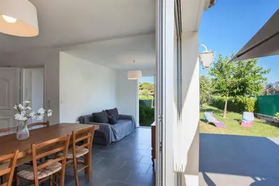 a dining room and living room with a table and a couch at Villa Jardins de la Mer in Poggio-Mezzana