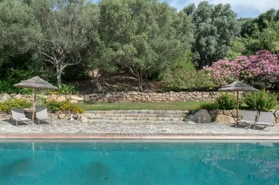 a swimming pool with two chairs and umbrellas at Residence Piatana in Olmeto