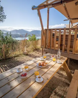 a wooden picnic table with food and glasses of orange juice at Residence Piatana in Olmeto