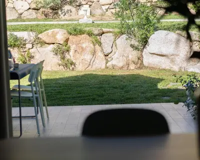 a patio with a table and chairs and a stone wall at Residence Piatana in Olmeto