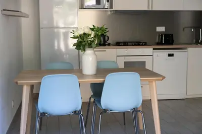 a kitchen with a wooden table with three blue chairs at Residence Piatana in Olmeto