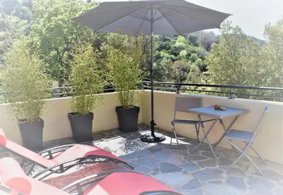 a patio with a table and an umbrella on a balcony at A Casa Di Campa in Oletta