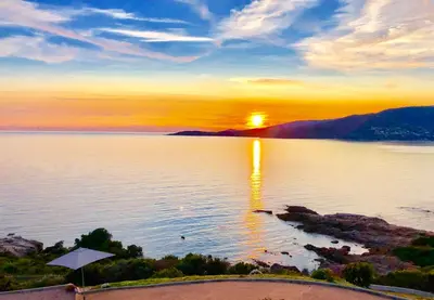 a sunset over a body of water with the sun setting at L'armandulina in Sagone